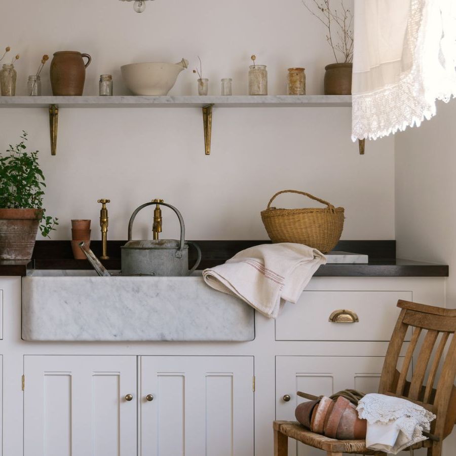 Utility sink area in cottage style home with open shelves and freestanding glass cabinet