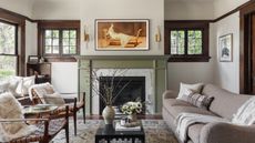 living room with green fireplace and white walls and wood framed windows