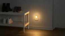a wall with a night light plugged into the wall and a shoe rack to the left 